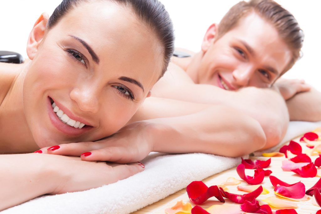 Couple relaxing with rose petals, smiling.