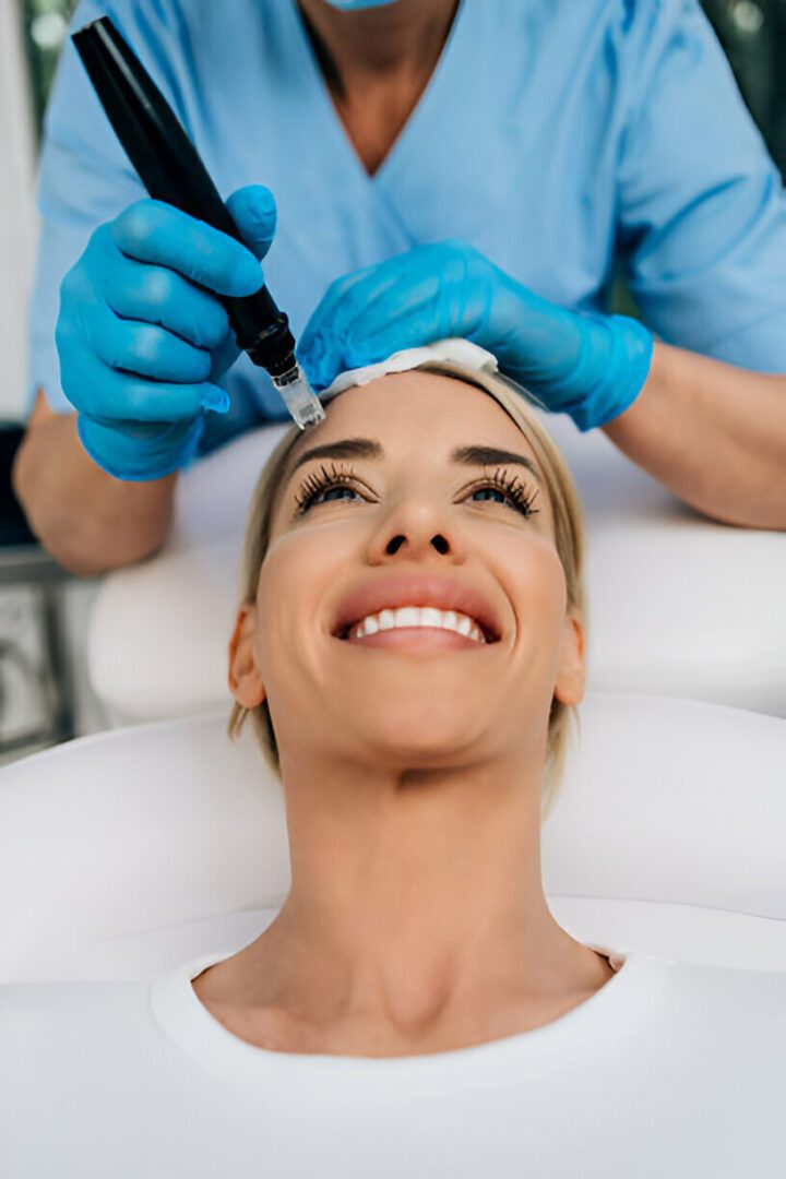 Woman receiving microneedling treatment, smiling.