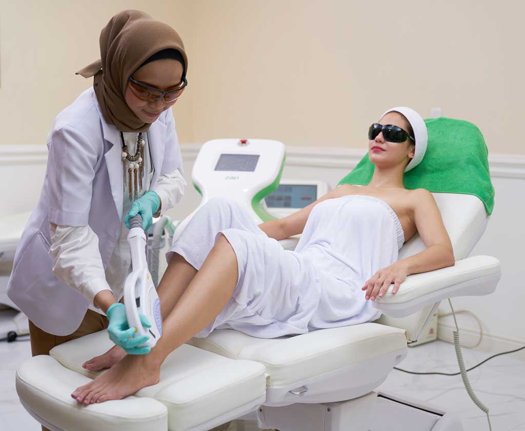 Woman receiving laser treatment on legs.