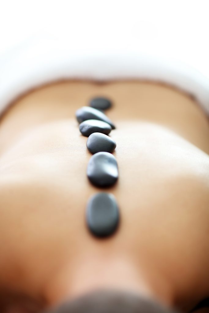 Hot stones aligned on a person's back.