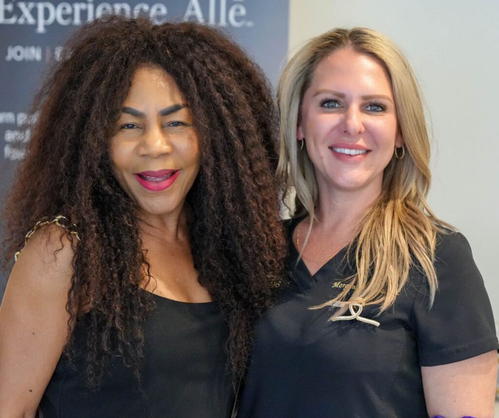 Two smiling women standing together in black tops