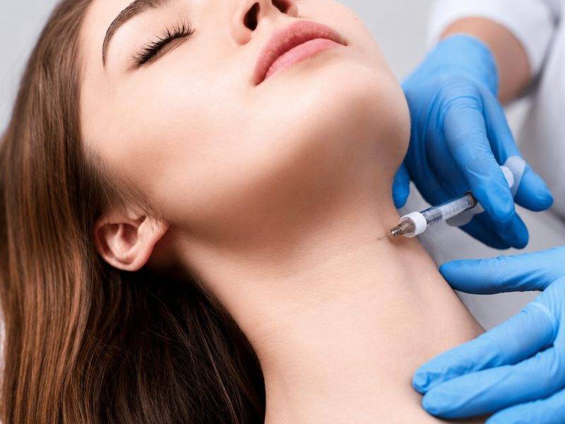 Woman receiving cosmetic neck injection procedure