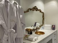 White robes hanging beside ornate gold bathroom vanity